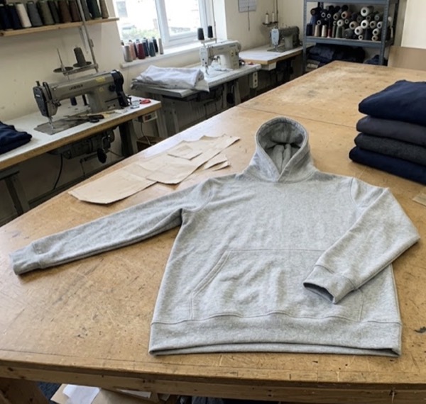 Original photo of a grey hoodie on a cutting table in a sewing workshop