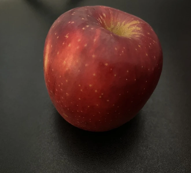 A man holding an apple against a plain background, illustrating the AI enhancement process in action.